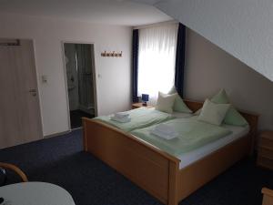 Schlafzimmer mit einem Bett mit grüner Bettwäsche und einem Fenster in der Unterkunft Am Alten Hafen in Neuharlingersiel