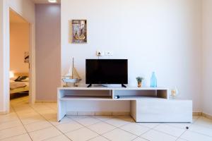 un soggiorno con TV su un centro di intrattenimento bianco di Cozy Home steps from old Port, Seafront & Parking a Kolymvari