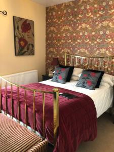 a bedroom with a bed with a red and gold wallpaper at The Langtons Bed & Breakfast in Eastbourne