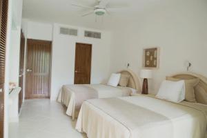 two beds in a room with white walls at Las Villas Akumal in Akumal