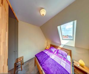 een slaapkamer met een bed met paarse lakens en een raam bij Haus Werder Wohnung 3 mit Kamin in Zinnowitz