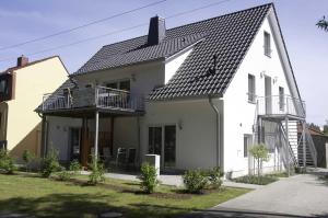 een wit huis met een zwart dak bij Haus Werder Wohnung 3 mit Kamin in Zinnowitz