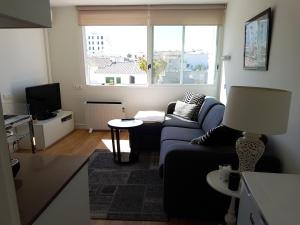 Una sala de estar con un sofá azul y una ventana. en Sitges - Apartamento, en Sitges