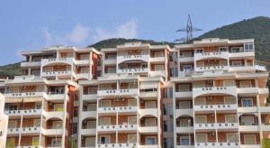 a large apartment building with a mountain in the background at Apartments Il Fiore in Vlorë