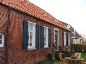 a red brick house with blue shutters and a table at Alte Pastorei in Hinte