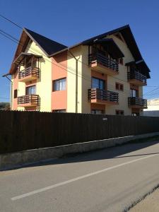 un edificio con balcones y una valla junto a una calle en Vila Teju Valeni, en Vălenii de Munte