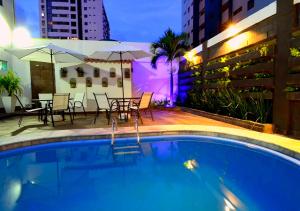 a swimming pool with a table and chairs next to a building at Pousada Boi Bumba Tambau in João Pessoa