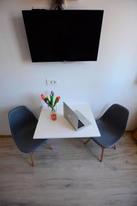 a white desk with a laptop and a vase of flowers at Nora Rooms in Zadar