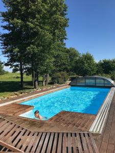 a woman laying in a swimming pool next to a wooden deck at Ranna puhkemaja in Lemsi