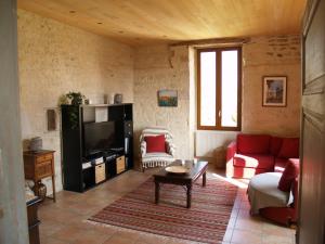 een woonkamer met een rode bank en een tv bij La Vayssade - Gîte de Charme - 6 pers - Piscine Jacuzzi & Truffes in Lalbenque