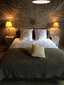 um quarto com uma cama grande com almofadas e 2 candeeiros em Le Charm'en Gîte em Tournai