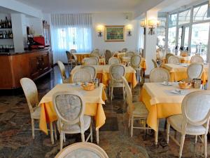a dining room with tables and chairs with yellow table cloth at Hotel Capri in Lesa