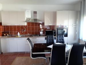 a kitchen with white cabinets and a table and chairs at Apartman Petra & Tena in Slunj