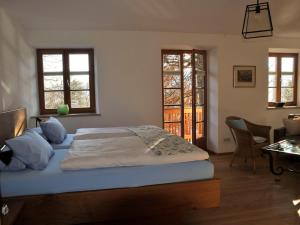 a bedroom with a bed and a desk and two windows at Malerhaus am Kolbergarten in Bad Tölz