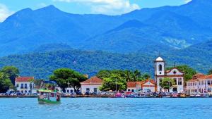 a boat in a body of water with mountains in the background at Casa em Paraty a 7 min. do Centro histórico in Paraty