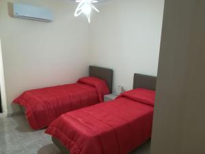 シラクーサにあるLa casa di Evaの赤い毛布が備わるドミトリールームのベッド2台