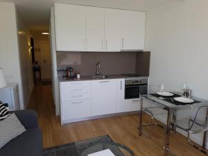 a kitchen with white cabinets and a table in a room at Sitges - Apartamento in Sitges