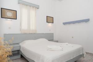 a white room with a bed and a window at Captain Manos Studio Apartments in Grikos