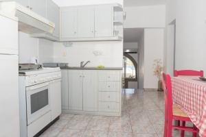 a kitchen with white cabinets and a table with red chairs at Captain Manos Studio Apartments in Grikos