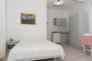 a white bedroom with a bed and a kitchen at Captain Manos Studio Apartments in Grikos