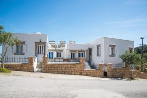 a house with a stone wall and a fence at Captain Manos Studio Apartments in Grikos