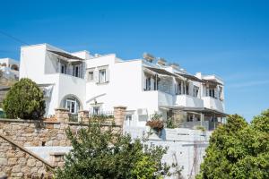 a white house on a hill with trees at Captain Manos Studio Apartments in Grikos