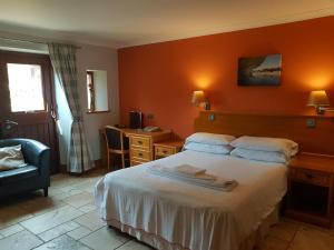 a bedroom with a bed and a desk and a chair at King's Head Inn in Llangennith