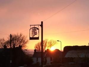 a pole with a sign in front of a sunset at King's Head Inn in Llangennith