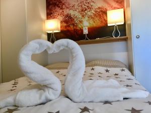 Una cama con dos cisnes haciendo un corazón en Friesland-cottage, en Molkwerum