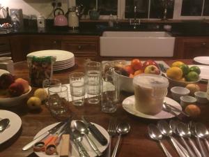 una mesa con platos y cuencos de fruta y cucharas en Ocean View B&B en Dingle