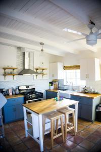 cocina con armarios azules y mesa de madera en M&L Desert Cottage - 6 min To North Entry Of JTNP!, en Twentynine Palms