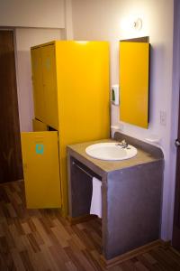 a bathroom with a sink and a yellow wall at Hostal Tres Central in Tuxtla Gutiérrez