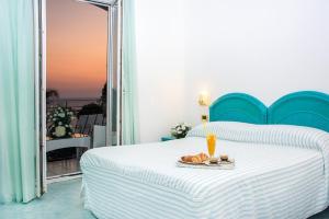a bedroom with a bed with a plate of food on it at Hotel Capizzo in Ischia
