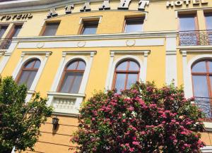 un bâtiment jaune avec des fleurs devant lui dans l'établissement Atlant Hotel, à Oujhorod