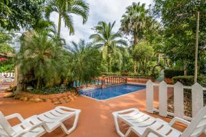 a group of white chairs and a swimming pool at Ara Ambigua Lodge in Sarapiquí
