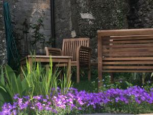 due panche e un tavolo in un giardino con fiori viola di La Stregatta a Triora