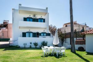 Casa blanca con mesa y sillas en el patio en Traditional Sea Side Cottage, en Máleme