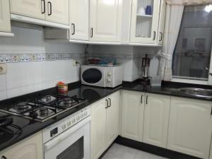 eine Küche mit weißen Schränken und einer Mikrowelle in der Unterkunft Apartamento con vistas en Raxó in Raxo