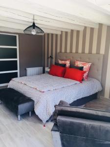 um quarto com uma cama com almofadas vermelhas e um sofá em Au Bord de La Dhuy em Orges