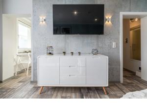 ein Wohnzimmer mit einem weißen Schrank und einem TV an der Wand in der Unterkunft Gepflegte und moderne Ferienwohnung in der Neuseenlandschaft in Neukieritzsch