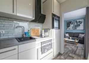 eine Küche mit einem Waschbecken und ein Wohnzimmer in der Unterkunft Gepflegte und moderne Ferienwohnung in der Neuseenlandschaft in Neukieritzsch