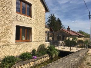 a building with a bridge next to a river at Au Bord de La Dhuy in Orges