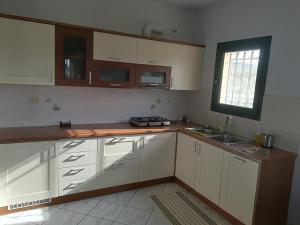 een keuken met witte kasten, een gootsteen en een raam bij Orfeas Villa in Kotróni
