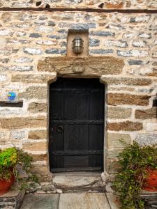 a black door in a stone building with plants at Mansion Karagiannopoulou in Vyzitsa