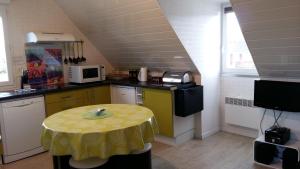 eine Küche mit einem Tisch und einem gelben Tischtuch darauf in der Unterkunft Appt-Gîte du Relais de Drugy in Saint-Riquier