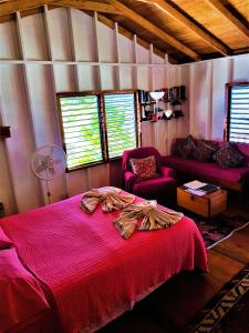 a bedroom with a red bed and a couch at Carolyn's House in Caye Caulker