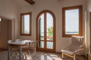 a living room with a table and chairs and windows at Cà Nicoletto by Venicevillas, Lido in Venice-Lido