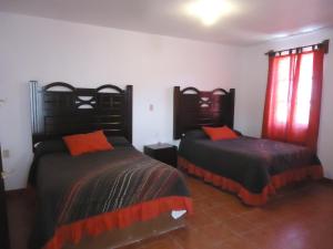 a bedroom with two beds with orange pillows at Hotel San Isidro in Bernal