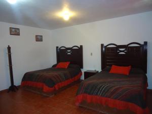 a bedroom with two beds with red pillows at Hotel San Isidro in Bernal