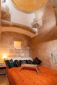 a bedroom with a bed with an orange comforter at Hamam Suites Sifaka in Chania